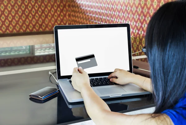 Women hands hold credit or debit card infront of blank screen notebook