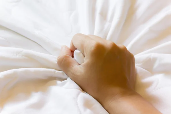 Hand grasp white bed sheet