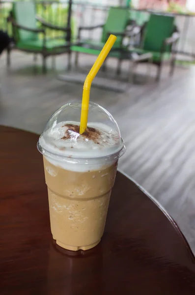 Capuchino coffee in take a way plastic cup on wooden chair