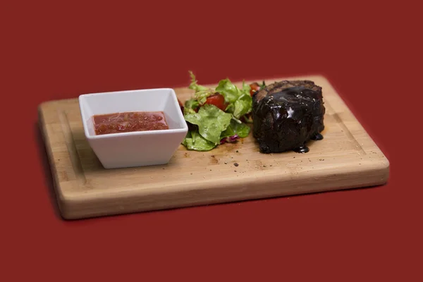 Delicious beef steak on wooden table, close-up. Grilled veal steaks with vegetables on cutting board.