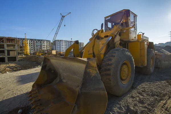 Bulldozer excavator on a construction site against the sky. Heavy buildind excavator in front of building site.