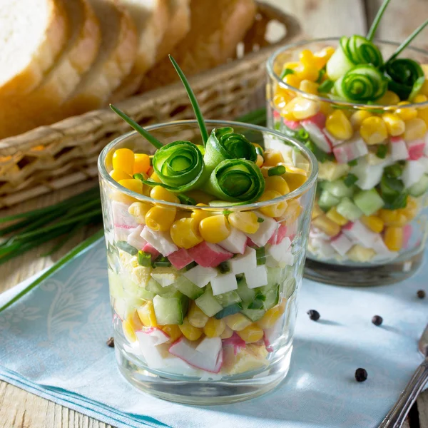 Salad with crab sticks, corn, cucumber and egg on a wooden table