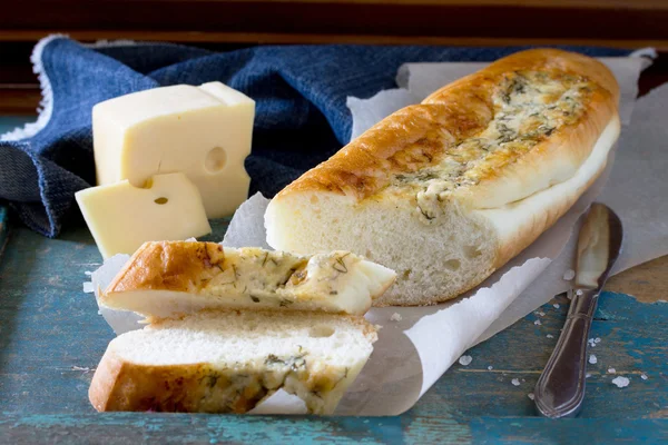 Bread long loaf baguette with cheese and herbs on a vintage wood
