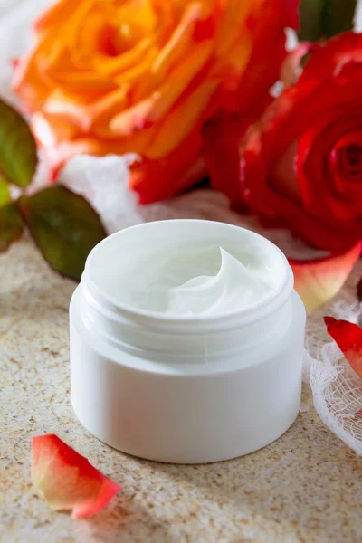 Face cream with roses on a brown stone fone- beauty salon.