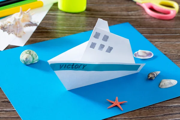 The child does crafts out of paper boat. Glue, paper, scissors o