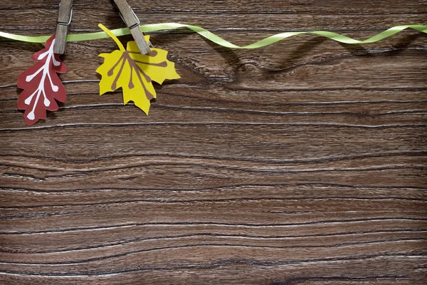 Autumn colored paper leaves on a wooden board