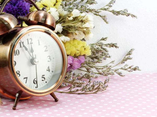 Spring time with alarm clock and statice flowers bouquet background