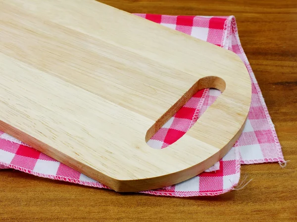 Wooden cutting board and tablecloth on wooden background