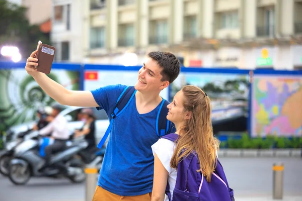 Hochiminh City, Vietnam - July 8, 2015: happy young couple walking on street doing selfie on Nguyen Hue Street, HoChiMinh city center