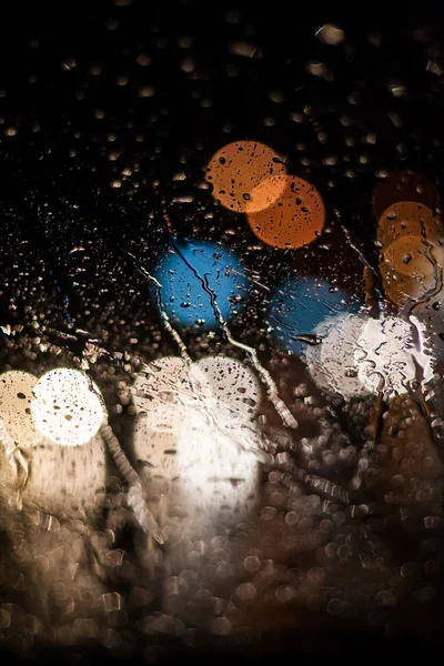 Drops of rain on window at night with bokeh lights background