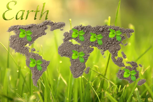 Earth Day. Concept ecology. World map, globe from the soil with green plants around the world on natural background