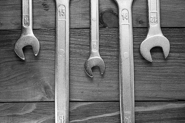 Set of wrenches. Wrenches in several different sizes on natural wooden background in black and white colours