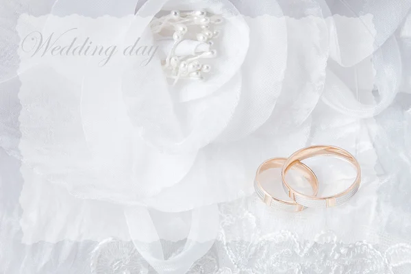 Wedding rings on wedding card, on a white wedding dress