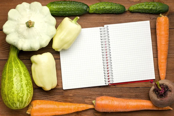 Fresh Organic Vegetables on a Wooden Background and Paper for Notes. Open Notebook and Fresh Vegetables Background. Diet. Health food. Space For Your Text.