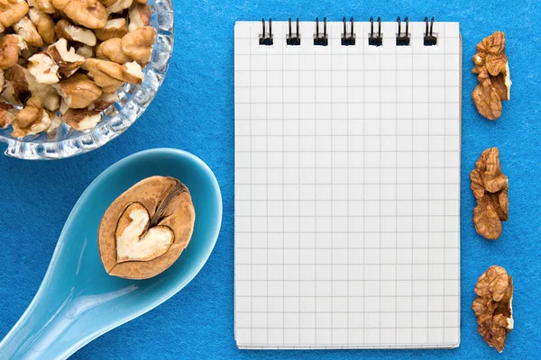Menu background. Cook book. Recipe notebook with walnuts on a blue background