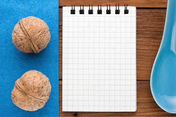 Menu background. Cook book. Recipe notebook with walnuts on a blue background and a wooden board.