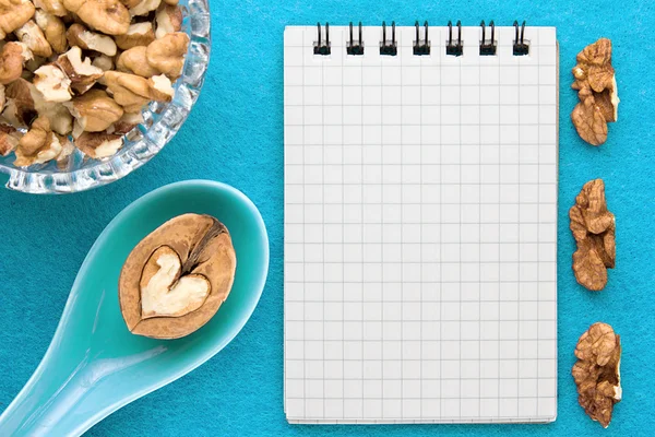 Menu background. Cook book. Recipe notebook with walnuts on a blue background