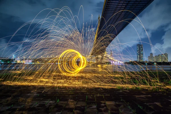 Hot Golden Sparks Flying from Man Spinning Burning Steel Wool under Bhumibol Bridge in Bangkok Thailand., Long Exposure Photography using Steel Wool Burning.