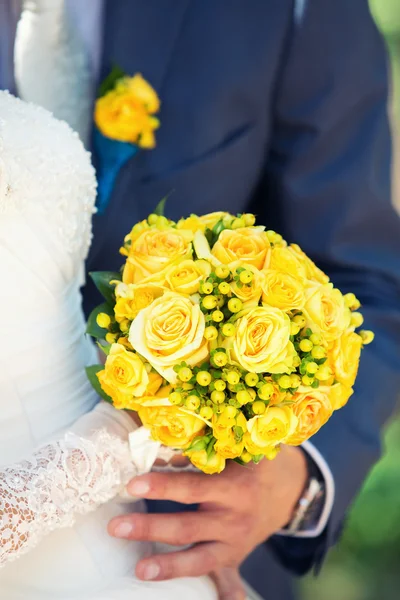 Bridal bouquet in the hands of newlyweds