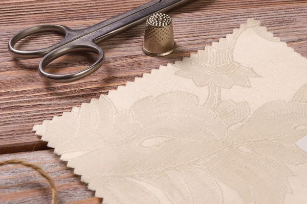 Textiles on a vintage wooden table with scissors and thimble