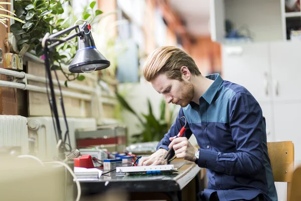 Handsome man soldering a circuit board