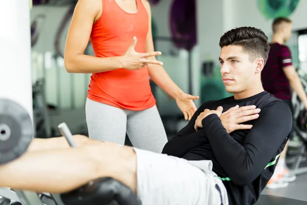 Beautiful woman instructing a man in the gym