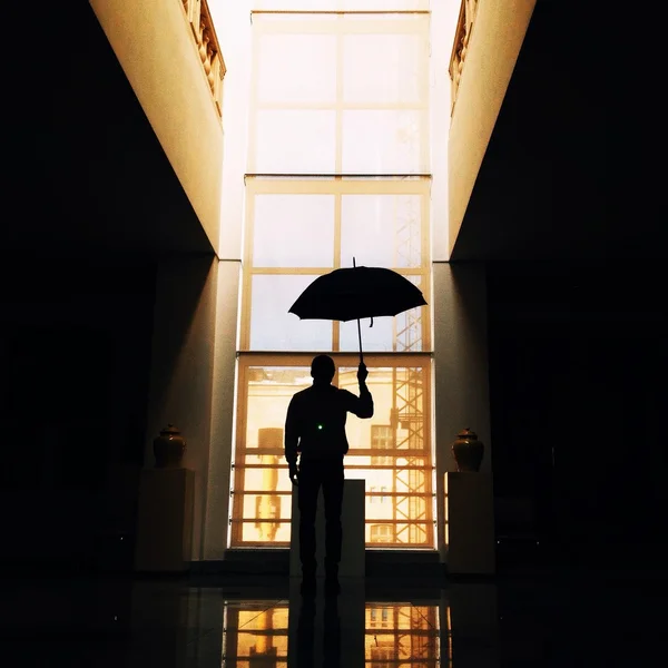 Man with umbrella in a building