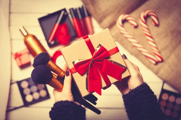 Hands are wrapping cosmetics in christmas gifts
