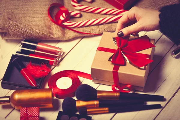 Hand are wrapping cosmetics in christmas gifts