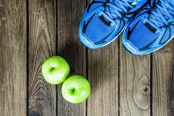 Sport shoes and apples  on a  wooden background. Sport equipment