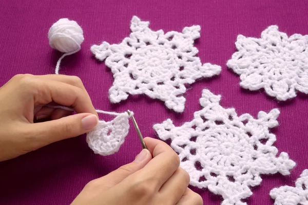 Woman knits crochet Christmas decoration - snowflakes