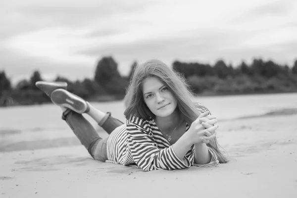 Girl resting on the beach, on the banks of the river. monochrome picture