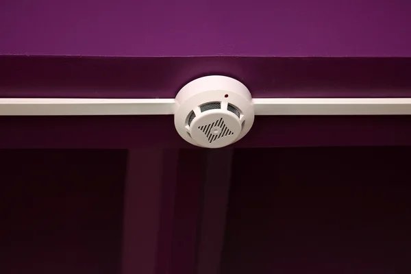 Fire sensor system on the background of violet ceiling