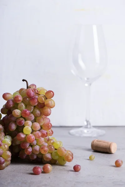 Fresh grapes with wine glass. Light background, copy space.