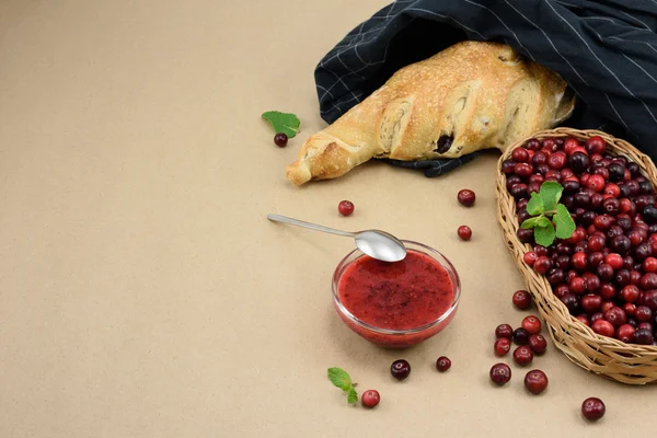 Fresh cranberry, french baguette and berries jam on bakery paper, selective focus, copy space.