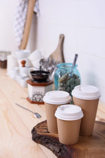 Coffee cups for take away, various sizes, and kitchenware on wooden lunch counter.