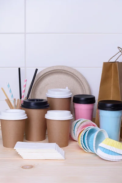 Coffee and tea cups for on the go. Paper and thermo mugs for hot or cold drinks on wooden bar counter. White background.