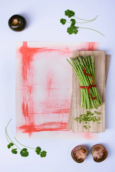 Fresh green asparagus and black tomato kumato on wooden board. Top view, copy space. .