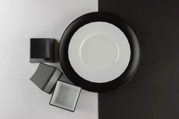 A number of flat plates and cups on black and white background