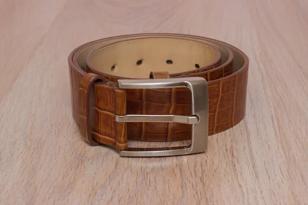 Leather belt with a buckle on a wooden board