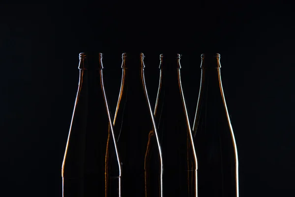 Silhouettes brown glass bottles for beer on a black background