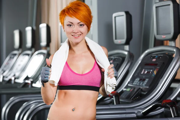 Young fit girl with red short hair in gym