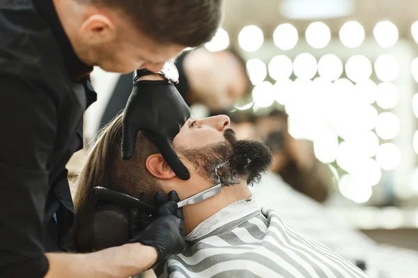 Barber making beard form for man