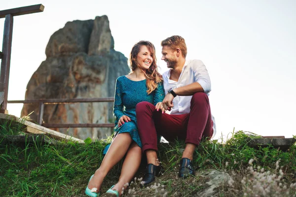 Nice couple sitting on grass near rock