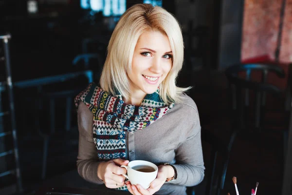 Girl sitting in cafe with cup of tea and smiling