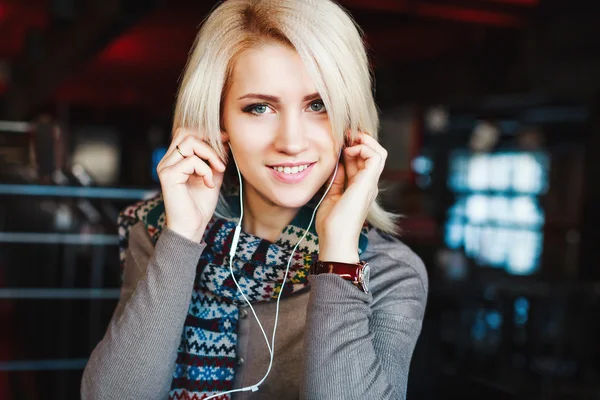 Cute blonde girl wearing headphones and smiling