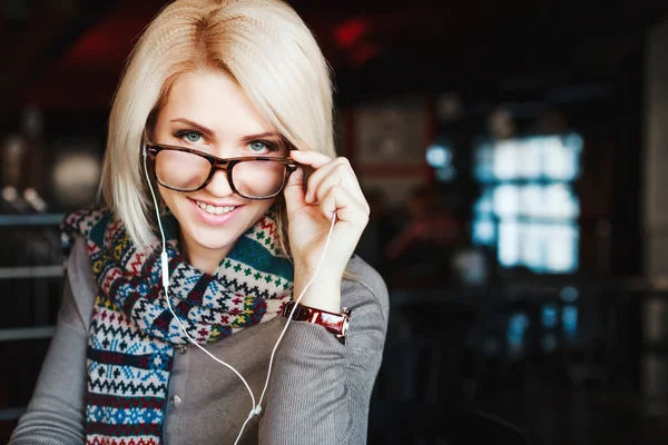 Blonde girl wearing headphones and glasses
