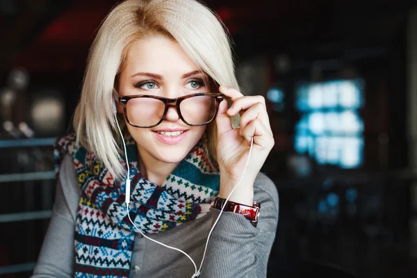 Blonde girl wearing headphones and glasses