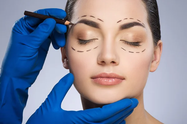Plastic surgeon drawing dashed lines above eyebrow