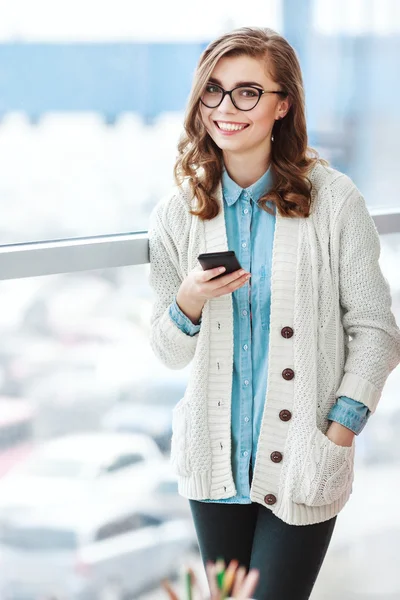 Girl with glasses standing with mobile phone